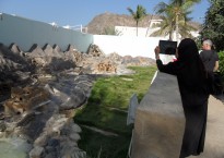 A young woman in her black abayah taking a photo with her Ipad is one way ot describing Oman today