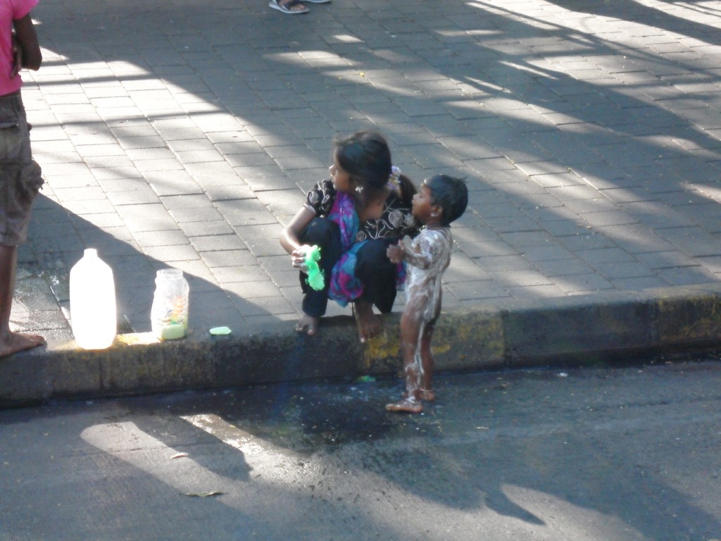 A young girl soaping down her baby brother (or child) on the street is not an unusual sight in Mumbai